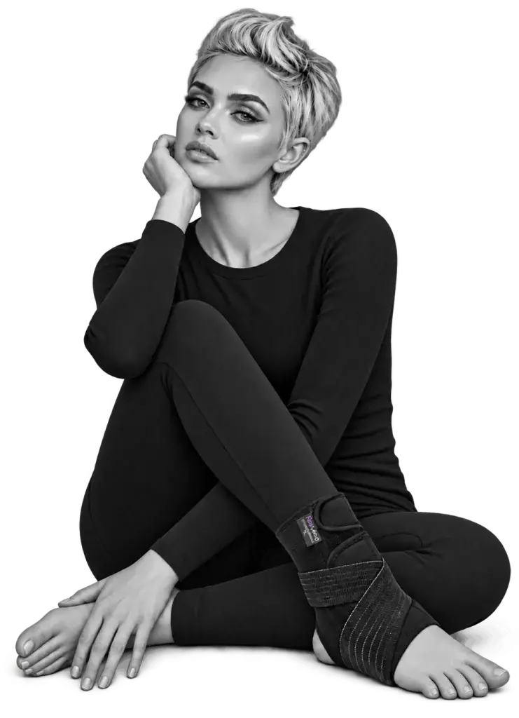 A woman seated on the floor wearing a Bodymap ankle support